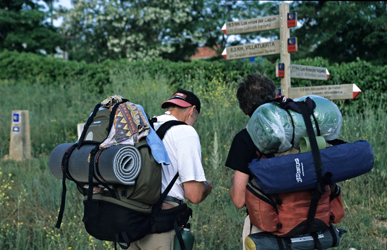 Buen Camino De Checco Zalone: O Caminho De Santiago Real E Como Fazê-Lo De Bike 2 Peregrinos Com Mochilas Diante De Uma Placa Do Caminho Em Navarra